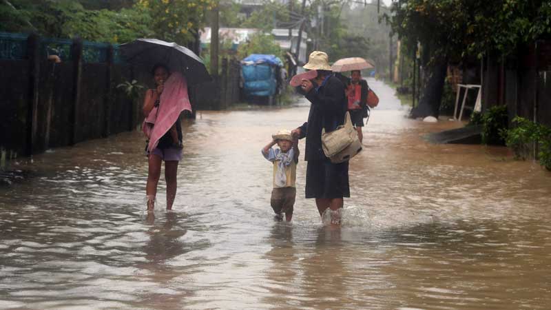 A family walks on a flooded street. FILE PHOTO