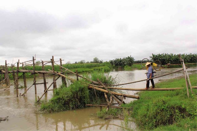 A CORN farmer crosses the makeshift wooden bridge in Barangay Tukanalipao, Mamasapano town in Maguindanao province six months after the  tragedy that killed 44 Special Action Force members. RICHEL V. UMEL/ INQUIRER MINDANAO