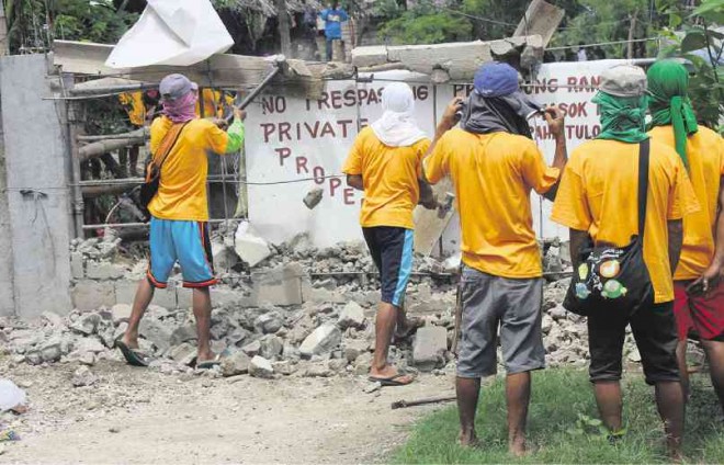GOVERNMENT workers demolish a wall of Hacienda Matias in San Francisco, Quezon province. FOOD FIRST INFORMATION AND ACTION NETWORK/CONTRIBUTOR