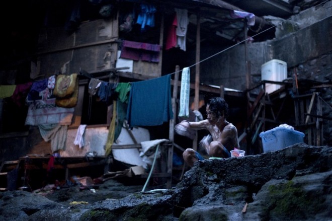 A member of one of thirty families who live under a bridge bathes in Manila. AFP PHOTO /NOEL CELIS