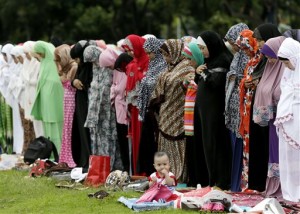 A baby girl sits by herself as Filipino Muslims pray at Rizal Park to mark the end of the holy month of Ramadan known as Eid al-Fitr Friday, July 17, 2015 in Manila, Philippines. Muslims all over the world mark the celebration of Eid with prayers, festivities and family reunions. AP PHOTO