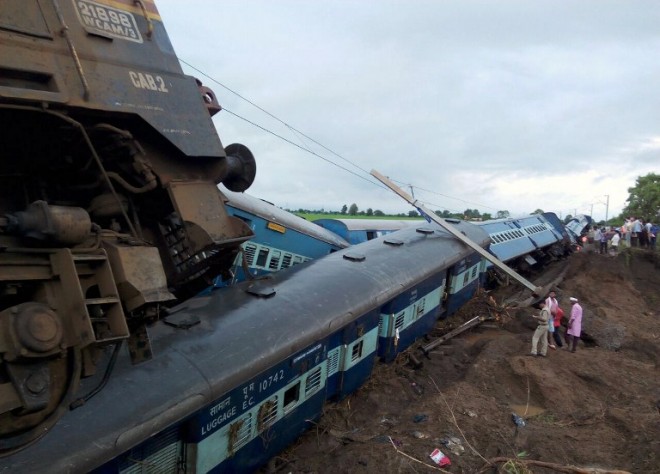 Indian officials stand next to two passenger trains on top of each other following a derailment after they were hit by flash floods on a bridge outside the town of Harda in Madhya Pradesh state on August 5, 2015. Two passenger trains derailed after being hit by flash floods on a bridge in central India, killing at least 27 people in the latest deadly accident on the nation's crumbling rail network. AFP PHOTO