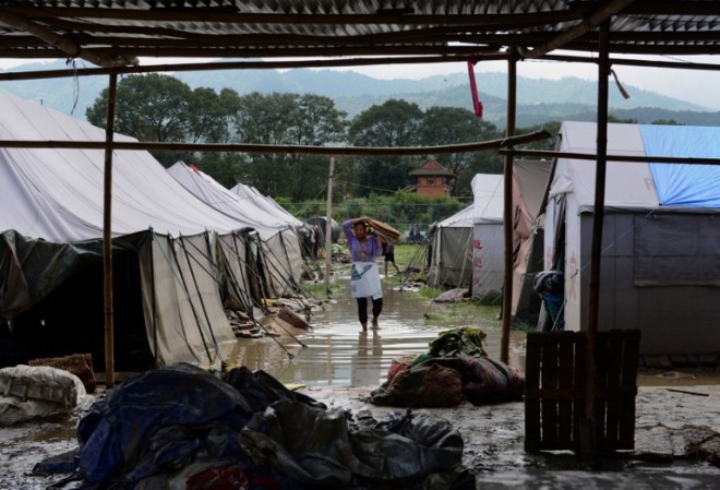 A Nepalese earthquake victim collects belongings from a temporary shelter after the Hanumente River overflowed following monsoon rain in Bhaktapur on the outskirts of Kathmandu on August 27, 2015. Monsoon rains are slowing rebuilding and relief efforts after nearly 8,900 people died and some 600,000 homes were reduced to rubble across the impverished Himalayan nation following the deastating earthquake that struck Nepal on April 25. AFP PHOTO / Prakash MATHEMA