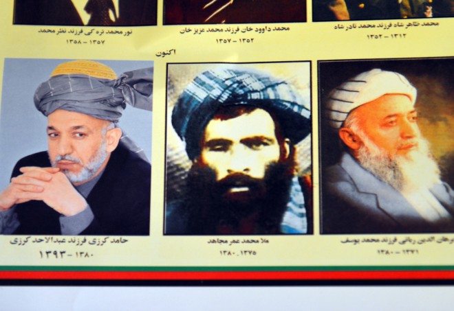 An Afghan shop clerk shows a calendar with pictures of Afghan leaders including Mullah Mohammad Omar, center, in Kandahar, south of Kabul, Afghanistan, Thursday, July 30, 2015. The Taliban confirmed the death of longtime leader Mullah Omar and appointed his successor Thursday, as a new round of peace talks was indefinitely postponed amid concerns over how committed the new leadership is to ending the militant group's 14-year insurgency. (AP Photo/Barialai Khoshhal)