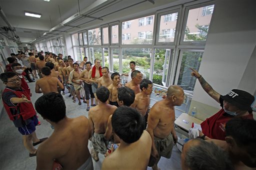 Evacuees line up for donated clothing at a temporary shelter at a primary school following explosions in northeastern China's Tianjin municipality, Thursday, Aug. 13, 2015. AP