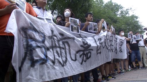 In this image taken from a video footage from AP Video, residents hold up a banner which reads: "Refugees from Qihang Apartment Complex appeal" outside a hotel where officials held daily media conferences in northeastern China's Tianjin municipality Sunday, Aug. 16, 2015.  AP VIDEO VIA AP