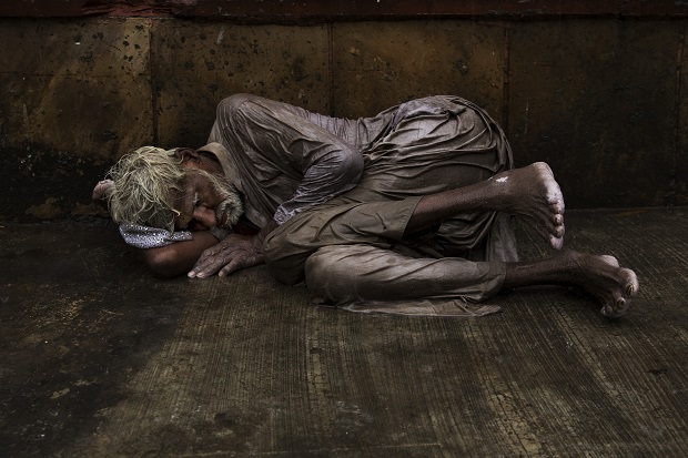 An Indian homeless man tries to sleep on a wet street during monsoon rains in New Delhi, India, Saturday, July 11, 2015. Tens of thousands of impoverished people live on the streets in New Delhi, where they struggle with constant hunger and extreme weather while sleeping nights next to busy intersections and roads. Some make camp in crowded alleyways, in abandoned lots or by garbage dumps. Many come from countryside villages in hopes of finding better economic opportunities in the Indian capital. (AP Photo/Bernat Armangue)