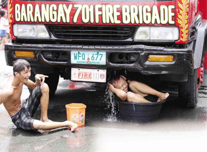 RESIDENTS of San Andres, Manila, take a bath as water spills from a fire truck going around “dry” areas. MARIANNE BERMUDEZ