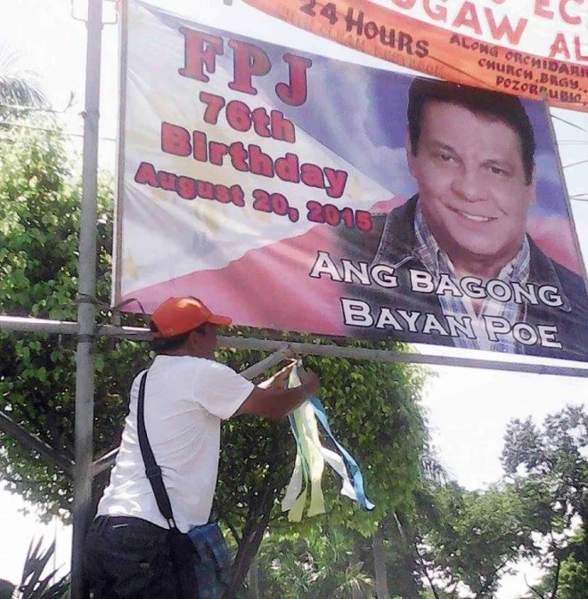 REMEMBERING ‘DA KING’ A volunteer ties a ribbon below a tarpaulin poster of the late actor Fernando Poe Jr. in Pozorrubio, Pangasinan province, in preparation for Poe’s 76th birthday today. CONTRIBUTED PHOTO 