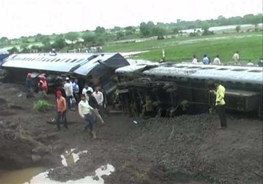In this image made from video, people gather by the scene where two trains derailed in Harda in Madhya Pradesh state, India, Wednesday, Aug. 5, 2015. Two passenger trains derailed over a bridge in central India while crossing a track that was flooded by heavy monsoon rains, killing at a number of people, officials said Wednesday. (Photo via AP Video)