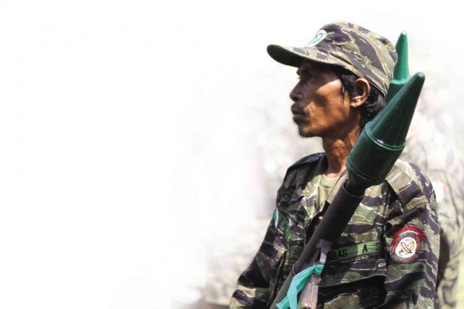 A MORO Islamic Liberation Front fighter carrying an antitank rocket-propelled grenade inside Camp Darapanan in Maguindanao province patiently waits for updates on the peace process with the government. RYAN D. ROSAURO