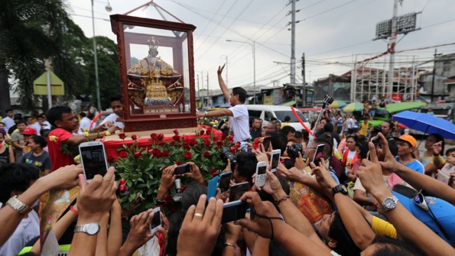 VISITOR FROM CEBU  Devotees take pictures with their cell phones and try to touch the image of the Santo Niño de Cebu as it is loaded onto the carriage in Guadalupe, Makati City, after a fluvial procession on the Pasig River on Sunday. The pilgrim image is on a five-day visit to Manila as part of the 450th anniversary of its “Kaplag” (discovery) by the Order of St. Augustine in 1565.  RAFFY LERMA