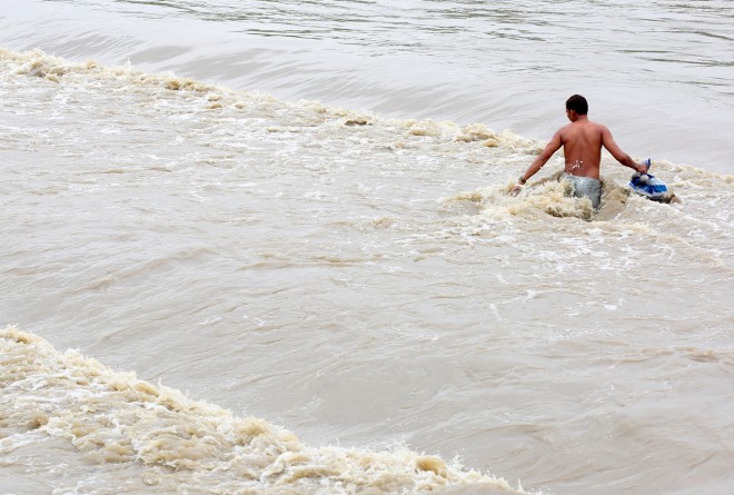 TYPHOON INENG / AUGUST 22, 2015 A resident collects recycleable materials despite the strong waves from the overflawed Tumana River, Marikina City, August 22, 2015, as earlier Saturday, the Philippine Atmospheric, Geophysical and Astronomical Services Administration issued rainfall warnings over 11 areas in Luzon including Metro Manila Saturday morning, with three Calabarzon provinces - Laguna, Cavite and Batangas - under orange rainfall category, meaning heavy rainfall with high threat of flooding, as a result of the southwest monsoon's being enhanced by typhoon Ineng (international name Goni). INQUIRER PHOTO / NINO JESUS ORBETA