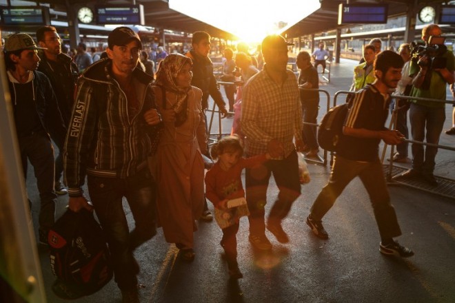 Migrants arrive at the railway station in Munich, southern Germany, during sunset on September 12, 2015. Arriving by the thousands, refugees stream in to the swamped southern German city of Munich, the entry point to their "Eldorado" which officials say is starting to burst from the influx. On Saturday alone "at least 10,000 people" were expected at the train station in the Bavarian capital, said Eva Hinglein, spokesperson for the Upper Bavaria district.  AFP PHOTO / PHILIPP GUELLAND