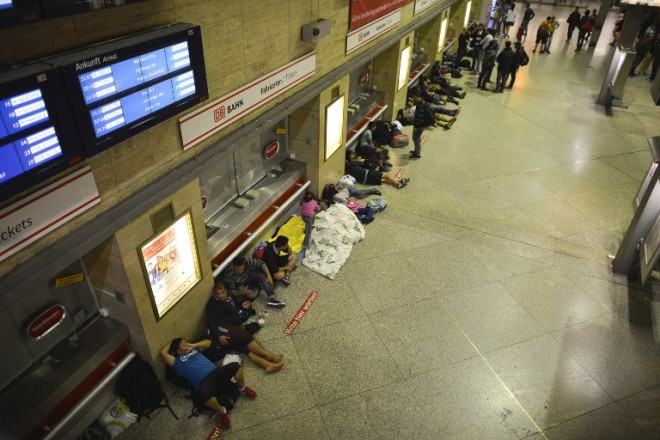 Migrants sleep at the central station on September 12, 2015 in Munich, southern Germany.   Munich is at the limit of its capacity to welcome refugees arriving en masse in Germany, police warned Sunday, a day after 12,200 asylum-seekers reached the city.  AFP PHOTO / PHILIPP GUELLAND