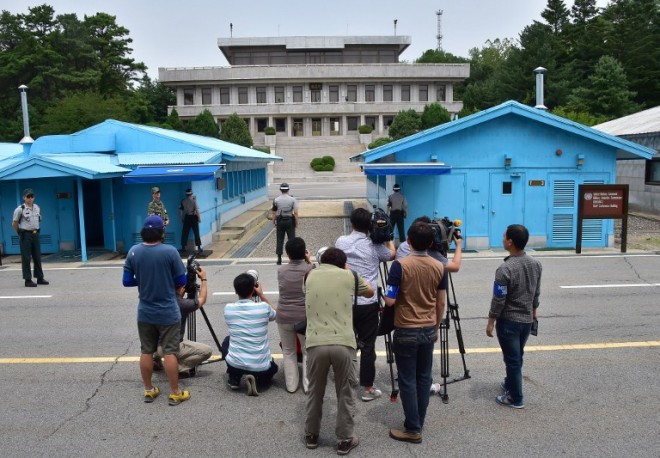 Cameramen take pictures of North Korean side during a press tour to the truce village of Panmunjom in the Demilitarized zone dividing the two Koreas on July 22, 2015.  North Korea is preparing to launch a new, long-range rocket, possibly in October, having completed an upgrade at its main satellite launch base, South Korea's Yonhap news agency reported. AFP PHOTO / JUNG YEON-JE