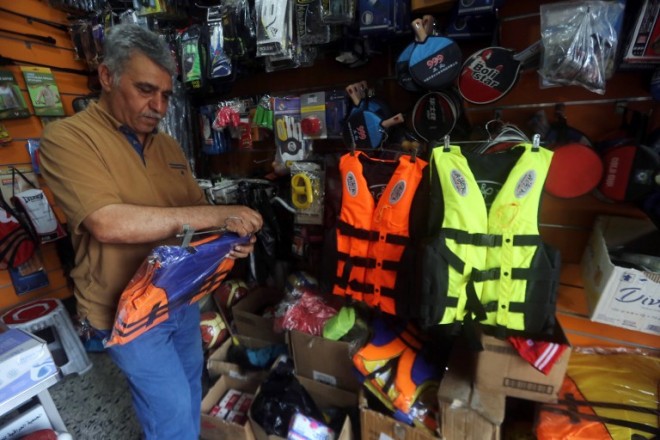 TO GO WITH STORY BY SALAM FARAJ AND W.G DUNLOP - An Iraqi man arranges life jackets at his shop on Rashid Street, where many of the Baghdad's sports shops are located on September 13, 2015, as demand for the survival vests has peaked with the increasing number of Iraqis trying to reach Europe by boat. Smugglers may not provide enough life jackets, and while estimates of costs vary, they are said to be much cheaper in Iraq than in Turkey, where the journey by boat to Greece begins. AFP PHOTO/ AHMAD AL-RUBAYE
