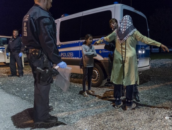 A policewoman controls a refugee mother and her daughter at the German-Austrian border near Piding, southern Germany, on September 14, 2015. After admitting that its capacity in the refugee crisis had been stretched to the limit, Berlin reintroduced identity checks on people travelling from the passport-free Schengen zone, and essentially announced an end to its open-doors policy to Syrians.     AFP PHOTO / GUENTER SCHIFFMANN
