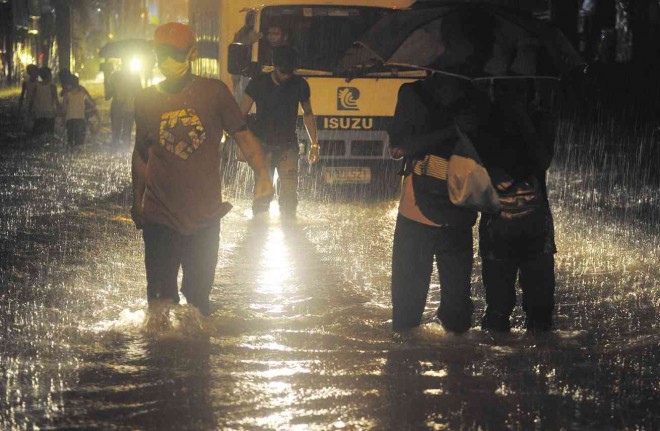WATERY WALK  Commuters choose to wade through floodwaters rather than be trapped in buses and other public transport immobilized by fast-rising waters after a sudden heavy downpour in suburban Manila on Tuesday night. Public officials blamed the high tide and the heavy rains for the floods, but stranded office workers and motorists pointed to road construction works, clogged drainage and too many vehicles on the road for the standstill.  AFP