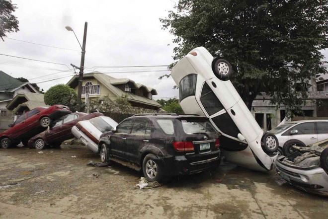 Cars tossed like dominoes (lower photo) show the fury of the September 2009 deluge.