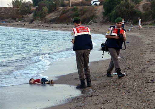  Paramilitary police officers investigate the scene before carrying the lifeless body of Aylan Kurdi, 3, after a number of migrants died and a smaller number were reported missing after boats carrying them to the Greek island of Kos capsized, near the Turkish resort of Bodrum early Wednesday, Sept. 2, 2015. AP