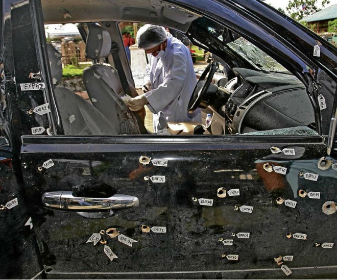 A member of the National Bureau of Investigation forensic team examines marks left by a hail of bullets that hit this SUV and another vehicle, and killed all 13 onboard, including police officers and soldiers in January 2013 in what is now called the Atimonan rubout. INQUIRER FILE PHOTO / RAFFY 