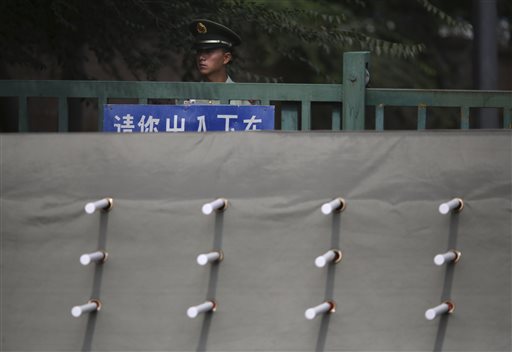 A Chinese paramilitary policeman stands watch behind a barrier leading to a side road outside the Japanese Embassy in Beijing, China, Wednesday, Sept. 30, 2015. China is holding two Japanese men on suspicion of spying, Japanese media reported Wednesday. Yoshihide Suga, Japan's top government spokesman, told reporters that Japan does its utmost to protect citizens abroad, but that he would not discuss specific cases. (AP Photo/Ng Han Guan)