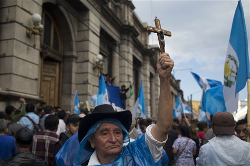 Nicolas Cabrera, 77, holds up a crucifix as demonstrators react in jubilation in front of the Guatemalan Congress building as they hear the news that Congress has voted to withdraw President Otto Perez Molina's immunity from prosecution, in Guatemala City, Tuesday, Sep. 1, 2015. AP