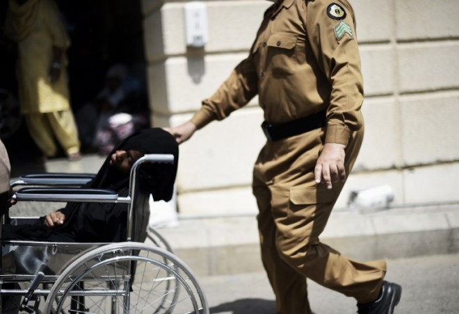 A Saudi policeman pushes a wheelchair with an injured pilgrim outside an emergency hospital following a deadly stampede in Mina, near the holy city of Mecca, on the first day of Eid al-Adha on September 24, 2015. At least 310 people were killed and hundreds wounded during a stampede at the annual hajj in Saudi Arabia, in the second tragedy to strike the pilgrims this year. AFP PHOTO/MOHAMMED AL-SHAIKH