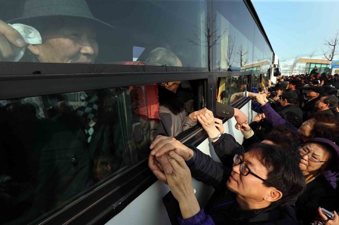 FILE - In this Feb. 25, 2014 file photo, South Koreans hold their North Korean relative's hands on a bus after the Separated Family Reunion Meeting at Diamond Mountain in North Korea. North and South Korea started talks at a border village Monday, Sept. 7, 2015,  on resuming the reunions of families separated by the Korean War in the early 1950s, Seoul officials said.  The highly emotional reunions have not happened since early last year. Most applicants are in their 70s or older and desperate to see their loved ones before they die.  (Lee Ji-eun/Yonhao via AP, File) KOREA OUT