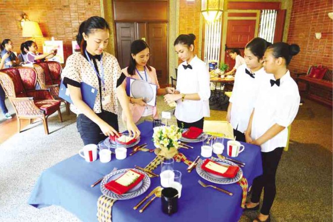 YOUNG women get hands-on training on the art of setting a proper table.