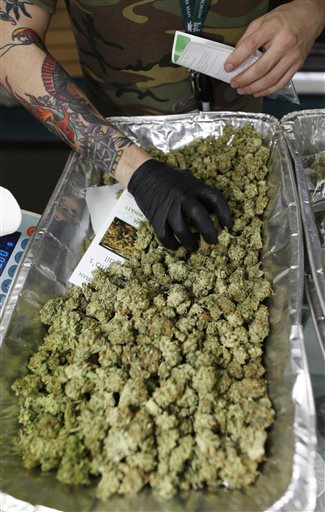 In this photograph taken Saturday, April 25, 2015, an employee loads packets with medicinal marijuana for sale as a contingent of lawmakers, their staffers and a handful of lobbyists toured one of two retail and grow operations for both medical and recreational marijuana in northeast Denver. Colorado's unusual tax law is forcing the state to suspend taxes on recreational marijuana for one day, Sept. 16, during which a 10 percent sales tax and a 15 percent excise tax will not be collected. (AP Photo/David Zalubowski)
