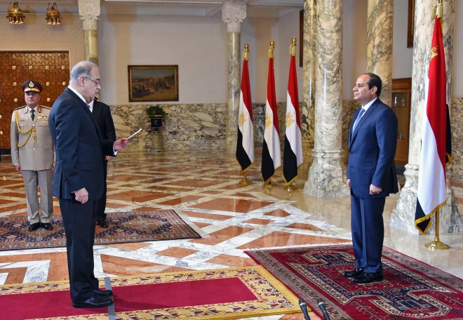 In this photo provided by Egypt's state news agency MENA, Egyptian President Abdel-Fattah el-Sissi, right, presides over the swearing in of Prime Minister Sheriff Ismail one week after the previous Cabinet resigned amid a corruption probe, in Cairo, Egypt, Saturday, Sept. 12, 2015. El-Sissi has also restructured the Cabinet, merging several ministries and forming a new body responsible for immigration, according to the Middle East News Agency. The 33-member Cabinet contains three women and 16 new members. (MENA via AP)