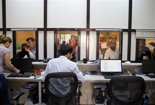 In this Tuesday, Sept. 15, 2015 photo, Syrian refugees  apply for passports inside their embassy, in Amman, Jordan. AP