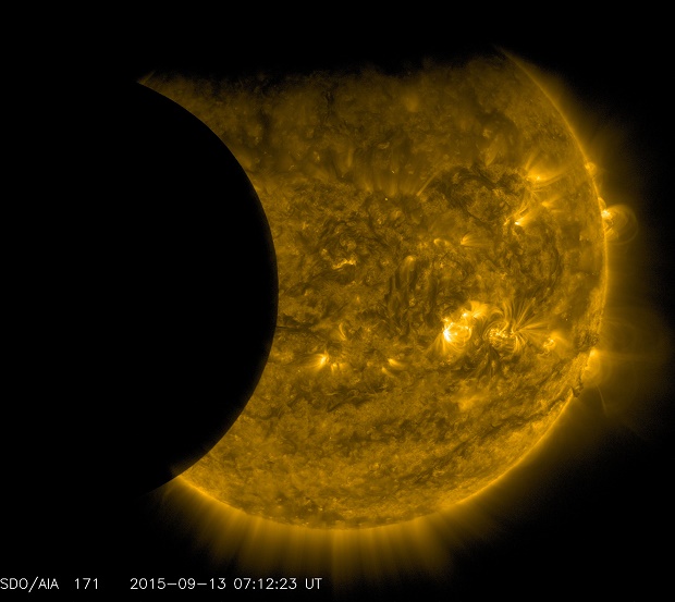This Sept. 13, 2015 image provided by NASA shows the moon, left, and the Earth, top, transiting the sun together, seen from the Solar Dynamics Observatory. The edge of Earth appears fuzzy because the atmosphere blocks different amounts of light at different altitudes. This image was taken in extreme ultraviolet wavelengths, invisible to human eyes, but here colorized in gold. A total lunar eclipse will share the stage with a so-called supermoon Sunday evening, Sept. 27, 2015 as seen from the United States. That combination hasn't been seen since 1982 and won't happen again until 2033. (NASA/SDO via AP)