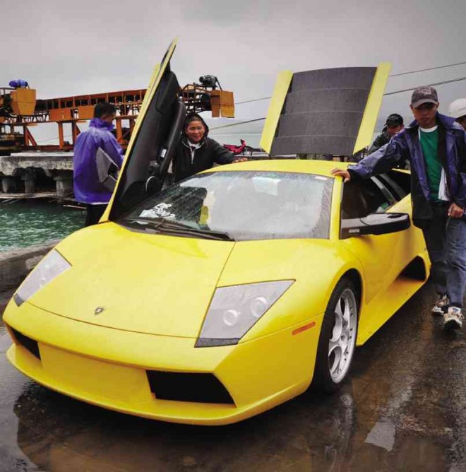 WORKERS help unload a sports car that was part of a shipment of second-hand vehicles that arrived in the Cagayan free port. PHOTOS BY MELVIN GASCON
