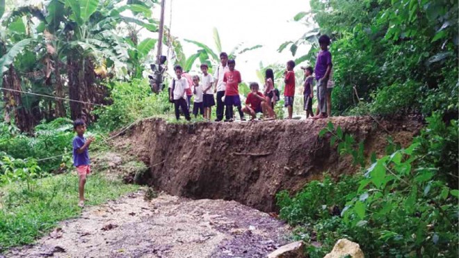 PUPILS look at the land cracks with a depth of at least 2.13 meters which appeared after continuous rains in Barangay Cantuyoc in Jagna, Bohol.     Leo Udtohan/ Inquirer Visayas