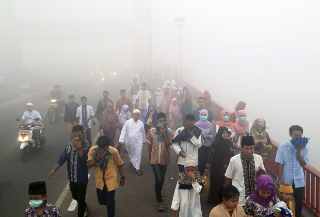 Muslims cover their mouths and noses from the haze from wildfires as they walk to attend a morning prayer marking the Eid al-Adha in Palembang, South Sumatra, Indonesia, Thursday, Sept. 24, 2015. Slash-and-burn practices destroy huge areas of Indonesian forest every summer during the dry season, creating haze that blankets parts of the archipelago and neighboring Malaysia and Singapore. (AP Photo)