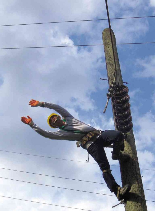 DEFYING GRAVITY A lineman hangs on a post to repair a transmission line in Pangasinan. CONTRIBUTED PHOTO