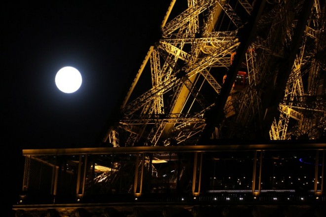 The moon appears behind the Eiffel Tower in Paris on September 27, 2015. For the first time in decades, skygazers are in for the double spectacle Monday of a swollen "supermoon" bathed in the blood-red light of a total eclipse. The celestial show, visible from the Americas, Europe, Africa, west Asia and the east Pacific, will be the result of the Sun, Earth and a larger-than-life, extra-bright Moon lining up for just over an hour from 0211 GMT. AFP PHOTO / LUDOVIC MARIN