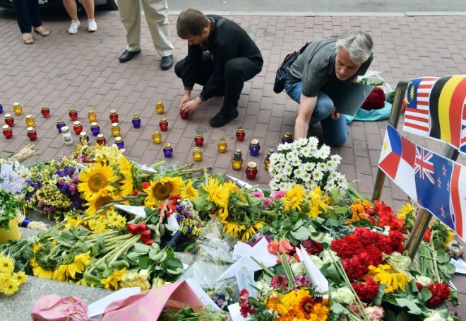 People lay flowers and light candles in front of the Dutch embassy in Kiev on July 17, 2015 in memory of the people who died in the crash of Malaysian Airlines flight MH17. All 298 passengers and crew, the majority Dutch, died on July 17, 2014 when the Malaysia Airlines Boeing 777, on a flight between Amsterdam and Kuala Lumpur, was shot down over rebel-held east Ukraine during heavy fighting between Ukrainian forces and pro-Russian separatists. AFP PHOTO/ SERGEI SUPINSKY