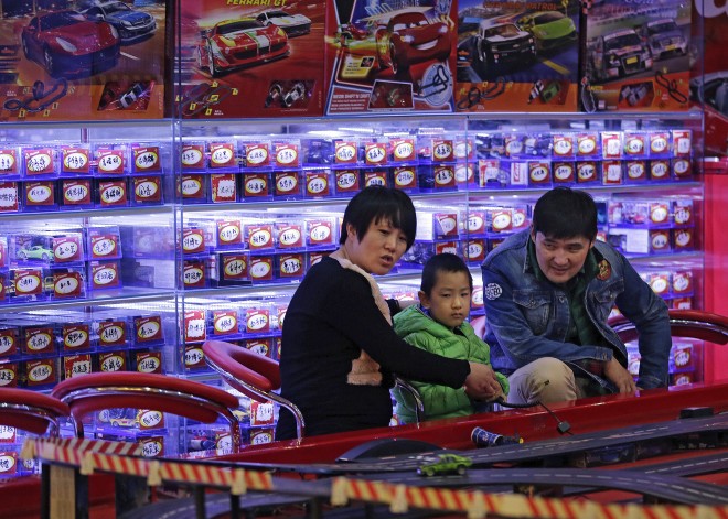 Parents and their child play with remote-controlled toy cars at a shopping mall in Beijing, Friday, Oct. 30, 2015. China's decision to abolish its one-child policy is a boon to couples and to sellers of goods from formula to diapers to toys. And it might help defuse economic stresses caused by an aging population. (AP Photo/Andy Wong)