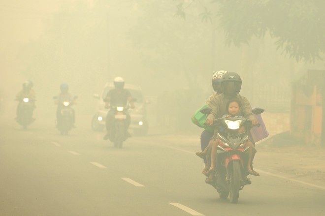 Motorists ride on a road as thick haze from forest fires shroud the city in Palangkaraya, Central Borneo, Indonesia, Tuesday, Oct. 27, 2015. The haze has blanketed parts of western Indonesia for about two months and affected neighboring countries like Singapore, Malaysia and Thailand. (AP Photos)