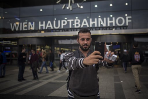 In this photo taken on Monday, Sept. 14, 2015, Mohammed al-Haj takes a photograph of himself in front of the central train station of Vienna, Austria. Mohammed, a 26-year-old from Aleppo, was one of more than 600,000 migrants and refugees who flowed into Europe so far this year. The Associated Press followed Mohammed on nearly every step of his 2,500-mile journey in September, starting from Killis, Turkey, where his family lived for a year after escaping Syria. (AP Photo/Santi Palacios)