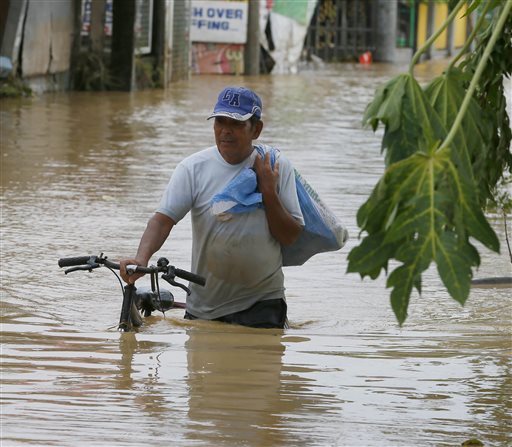 A resident pushes his bicycle as he wades through floodwaters caused by Typhoon Koppu at Zaragosa township in Nueva Ecija province, north of Manila, Philippines Monday, Oct. 19, 2015. The slow-moving typhoon blew ashore with fierce wind in the northeastern Philippines early Sunday, toppling trees and knocking out power and communications and forcing the evacuation of thousands of villagers. (AP Photo/Bullit Marquez)