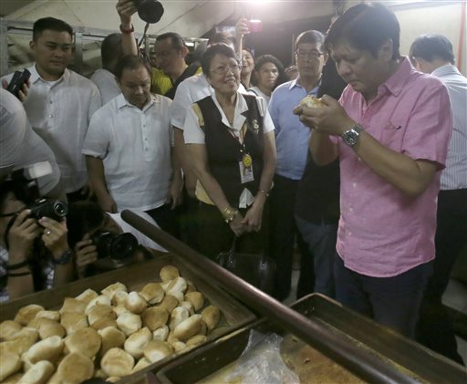 Philippine Senator Ferdinand "Bongbong" Marcos Jr. samples a local bread known as "Pandesal" following a media forum Wednesday, Oct.7, 2015, two days after announcing he is seeking the nation’s second highest office in next year’s national elections, at suburban Quezon city northeast of Manila, Philippines. Marcos Jr., the son of the late dictator Ferdinand Marcos,  said that Filipinos are no longer concerned with abuses committed under his father’s rule, angering human rights activists who say he wants people to forget his father’s strongman rule that a popular revolt ended 29 years ago. (AP Photo/Bullit Marquez)