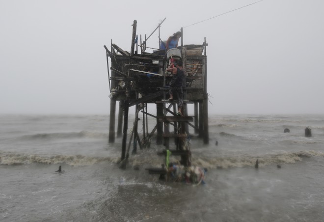 Residents carry their belongings up their house on stilts as strong winds and rains caused by Typhoon 'Lando' hits the coastal town of Navotas, north of Manila, Philippines on Sunday, Oct. 18, 2015.  AP