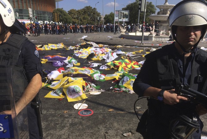 Bodies of victims are covered with flags and banners as police officers secure the area after an explosion in Ankara, Turkey, Saturday, Oct. 10, 2015. Two bomb explosions apparently targeting a peace rally in Turkey's capital Ankara on Saturday has killed many people  a news agency and witnesses said. The explosions occurred minutes apart near Ankara's train station as people gathered for the rally organized by the country's public sector workers' trade union. (AP Photo/Burhan Ozbilici)