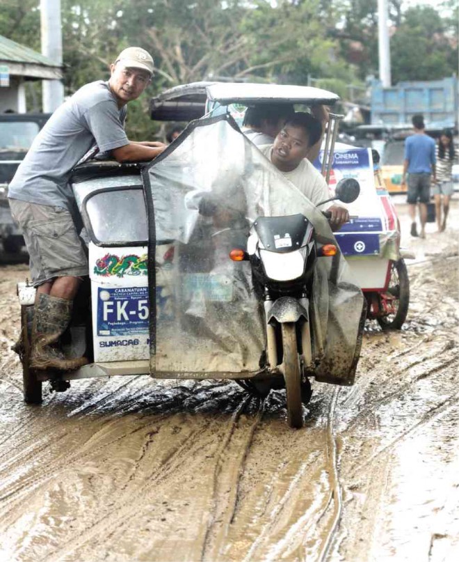 A TRICYCLE negotiates a muddy road in Cabanatuan City on Oct. 20 as floodwaters brought by Typhoon “Lando” (international name: Koppu) subside. GRIG C. MONTEGRANDE