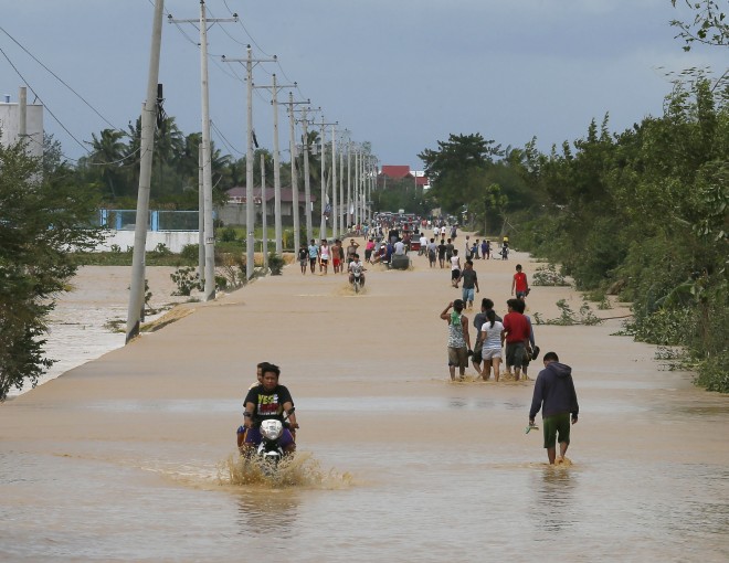Residents wade through floodwaters brought about by Typhoon Koppu at Zaragosa township, Nueva Ecija provinc,e north of Manila, Philippines Monday, Oct. 19, 2015. Slow-moving Typhoon Koppu blew ashore with fierce wind in the northeastern Philippines early Sunday, toppling trees and knocking out power and communications and forcing the evacuation of thousands of villagers.(AP Photo/Bullit Marquez)